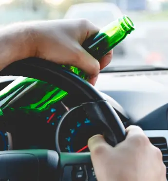 man holding a steering wheel with a beer